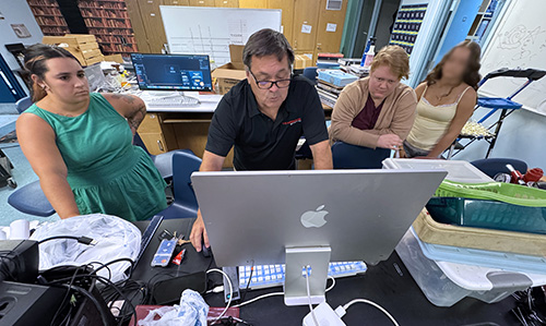Lance Baker works with advisers and a yearbook student.